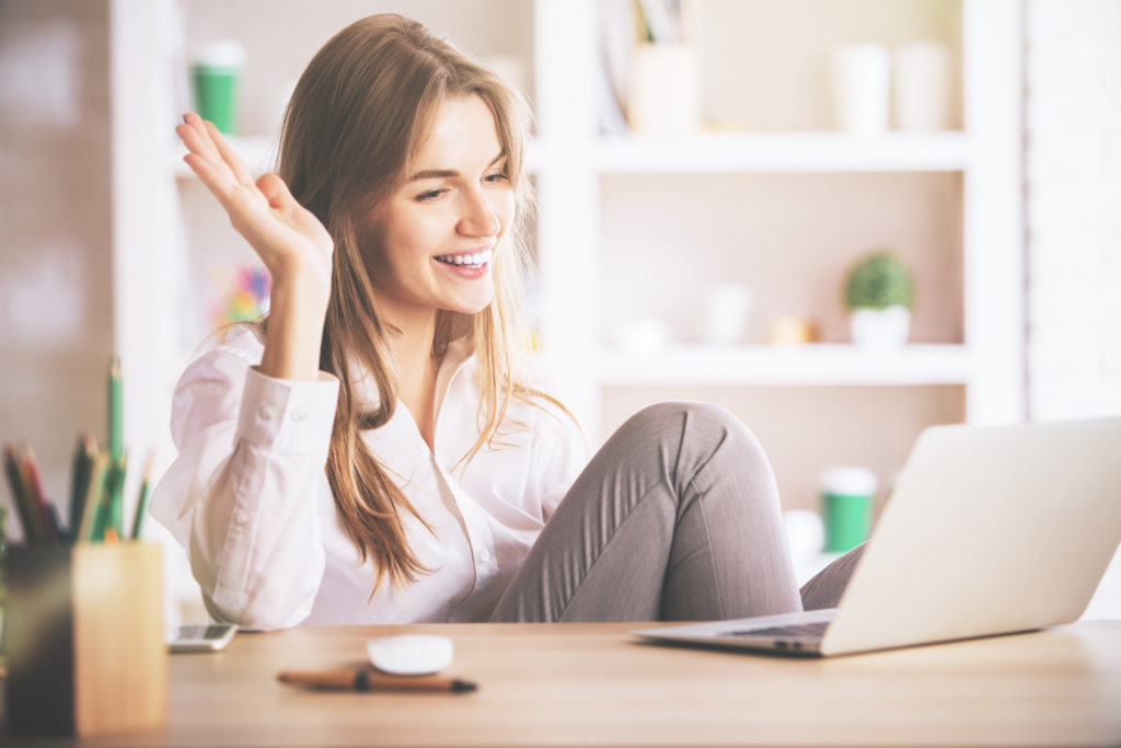 Portrait of gorgeous, smiling young lady using laptop computer at workplace