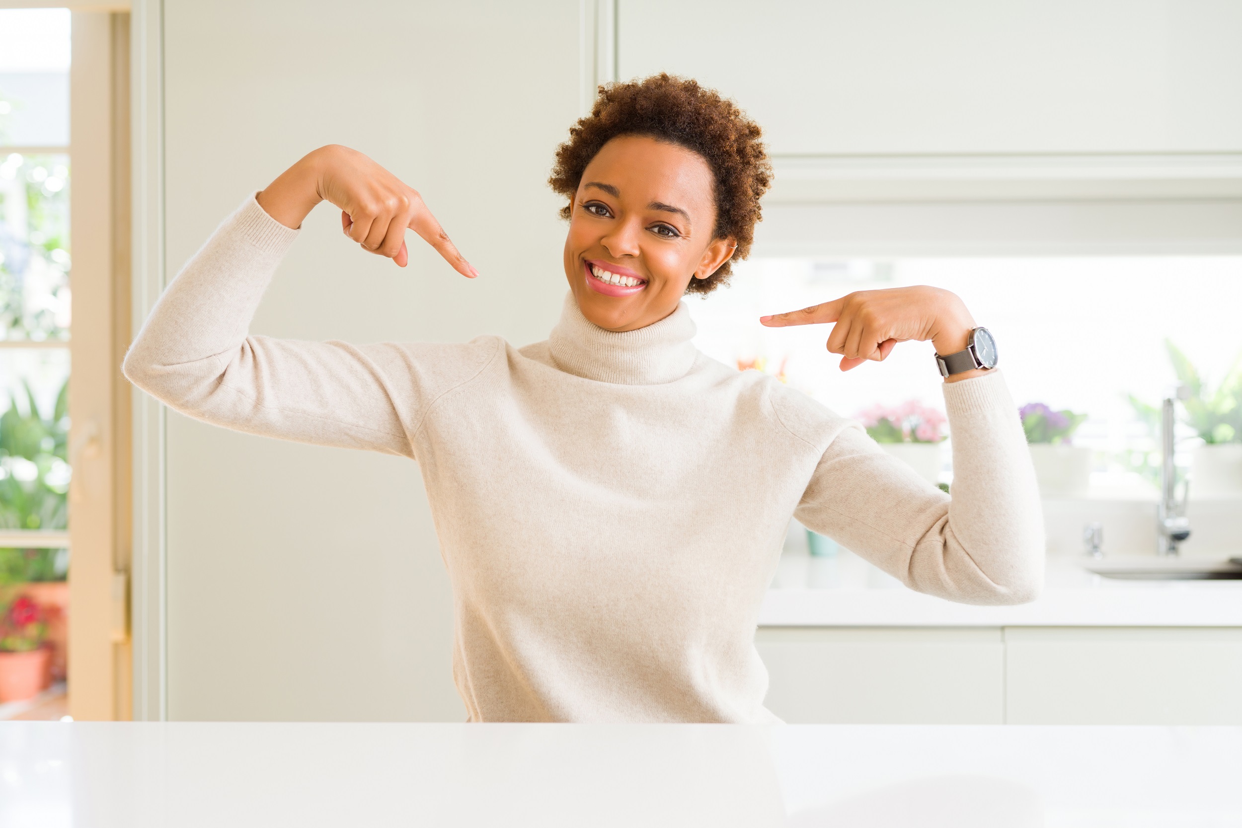 Young beautiful african american woman at home looking confident with smile on face, pointing oneself with fingers proud and happy.