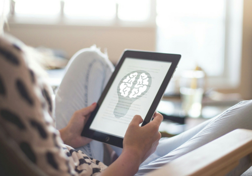 Mindset Assessment image - woman holding a tablet with a lightbulb brain on it