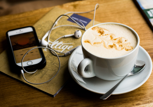 Podcast image - latte next to a smartphone and headphones