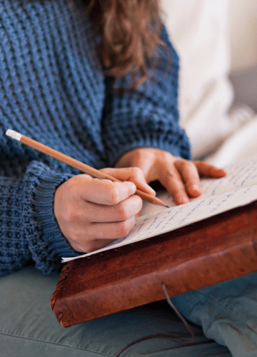 woman's hands writing in a journal